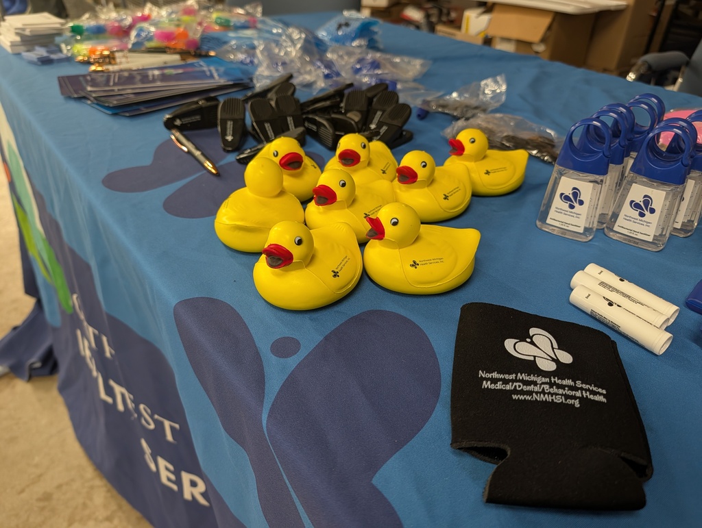 A blue table with a tablecloth and various yellow rubber ducks, bottles, a pen, and a black cloth.