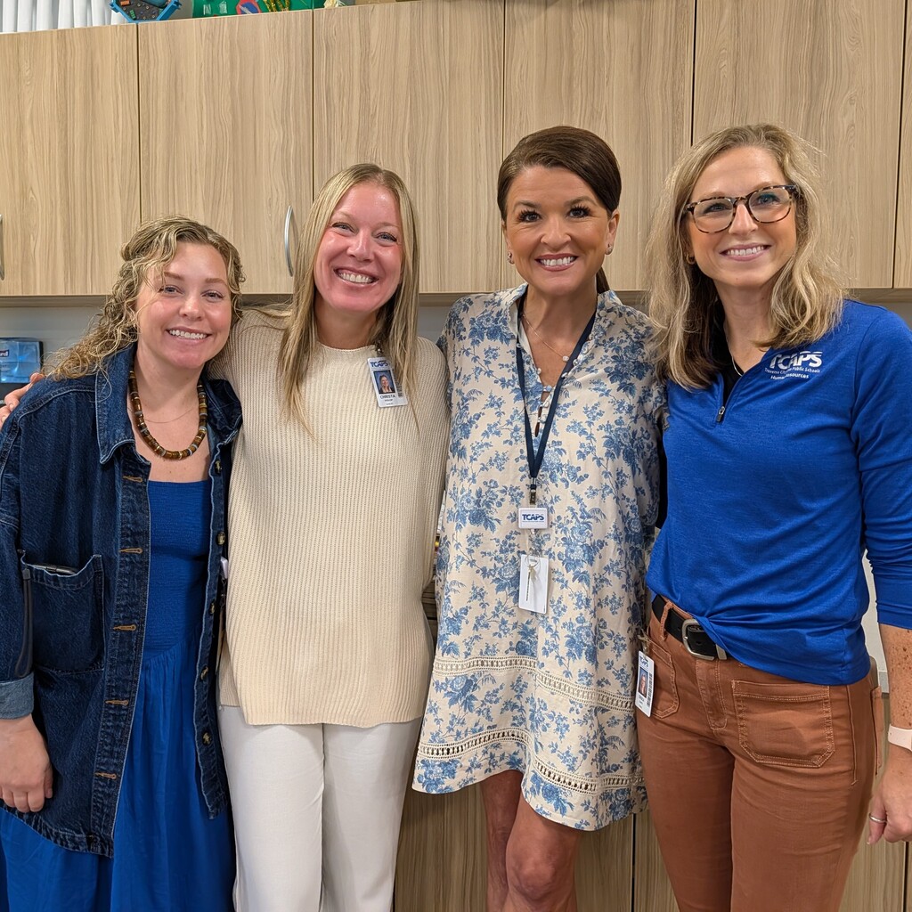 Staff members smiling for pictures at new teacher orientation. 