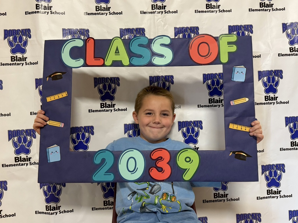 Kindergarten student holding a "class of 2039" sign.