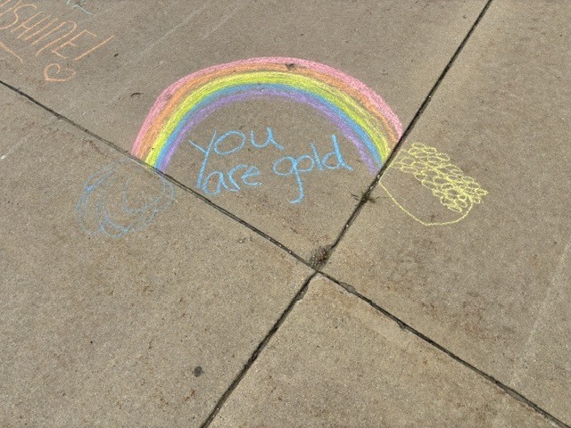 Sidewalk with colorful chalk art of a rainbow and the words "You are gold" written in blue.