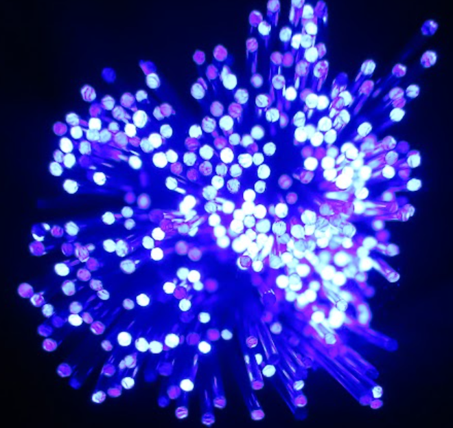 A cluster of blue and purple lights resembling a flower on a dark background.