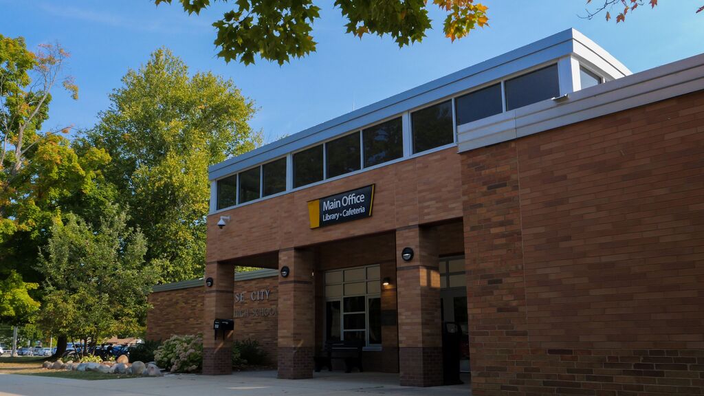 Front of a brick building with large glass windows, a white sign reading "Main Office" above the entrance.
