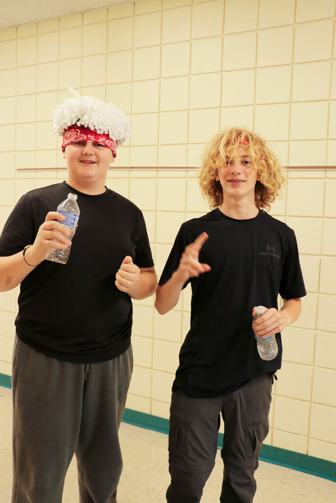 Two young men, one with a white hat and red bandana, standing next to each other with water bottles in their hands.