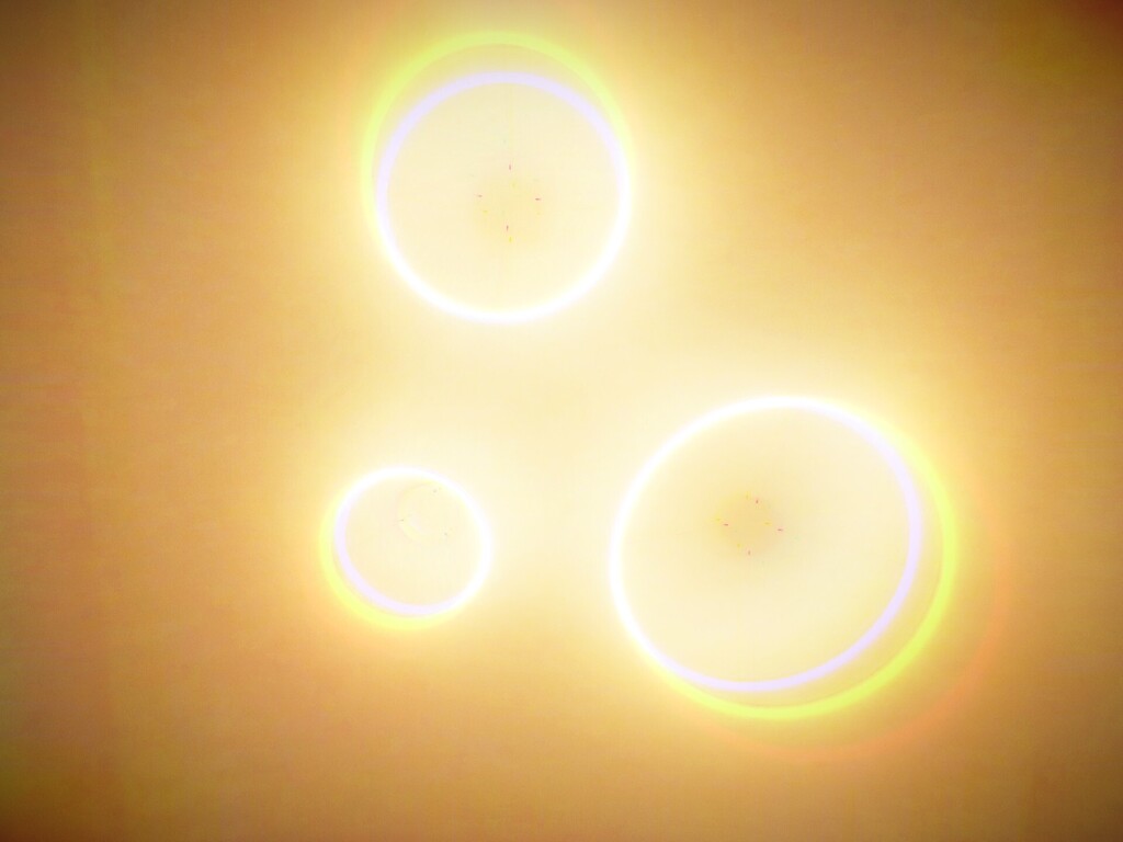 Three glowing circles with light reflections on a yellow background. The middle circle has a small white dot.