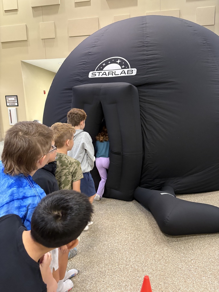 Six children stand around a large inflatable dome with the word "Starlab" on it.