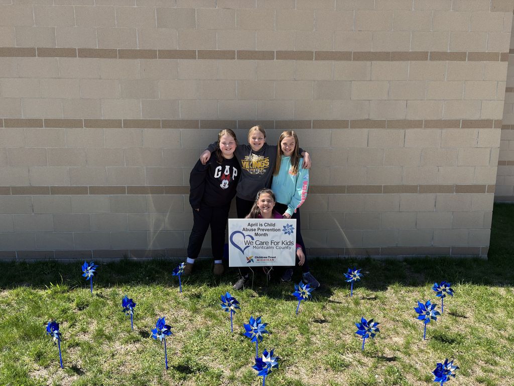 Students with a sign and a blue pinwheel garden.