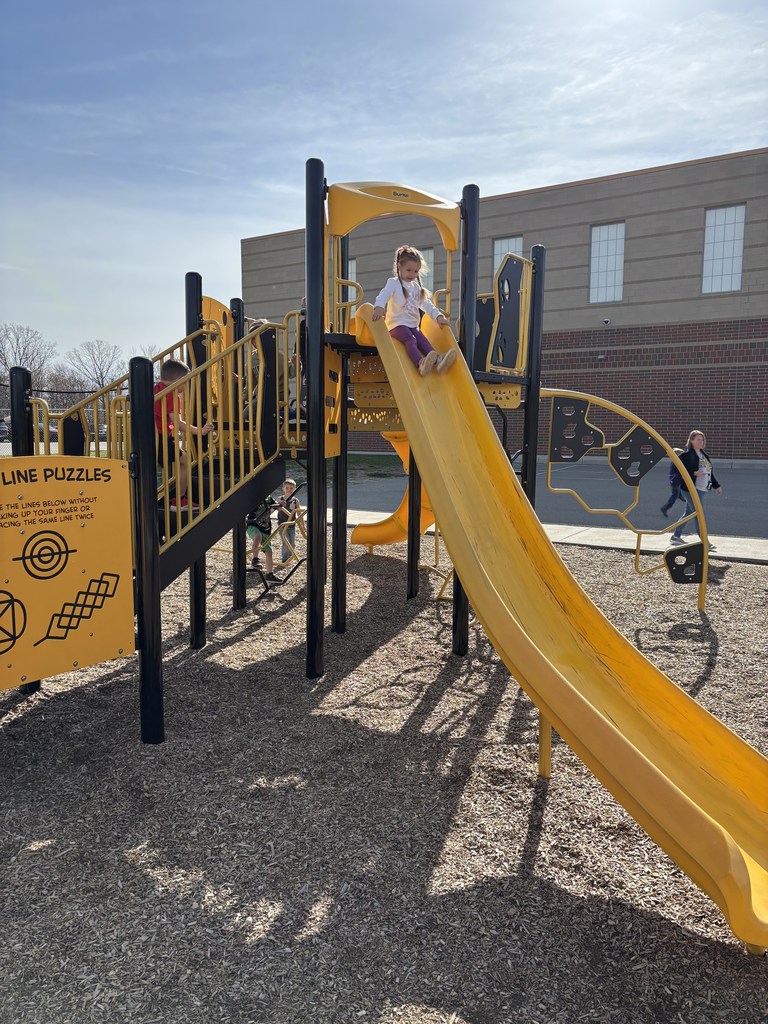 Preschooler sliding down the slide at the elementary school.