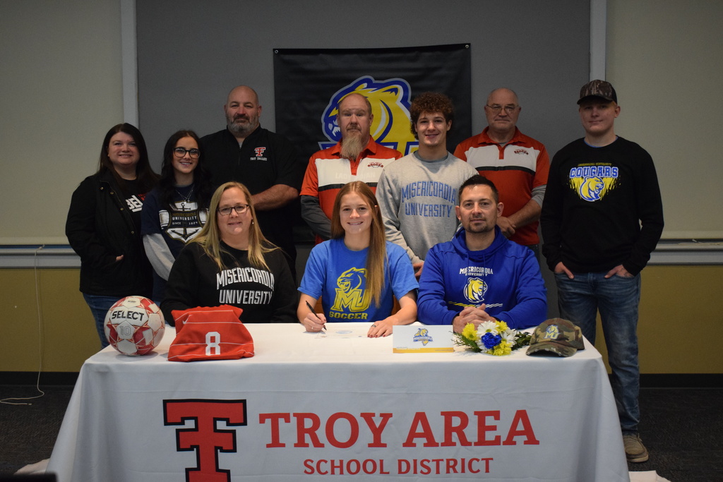 Student college signing with coaches, family and staff