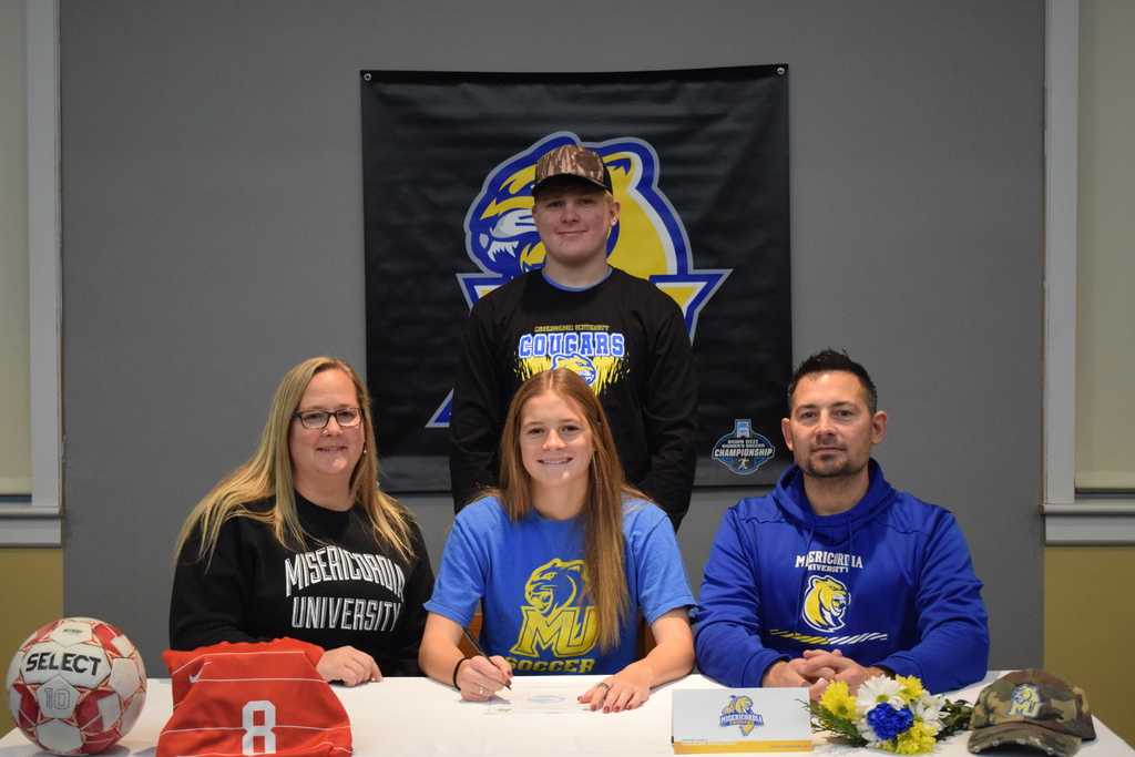 Student signing for college with family