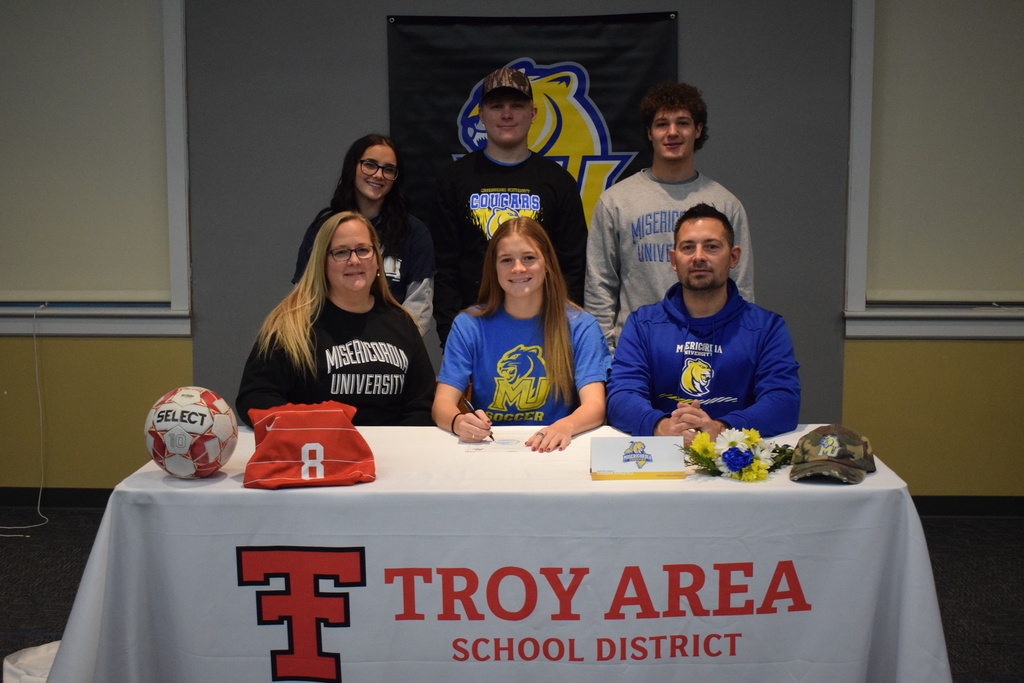 student signing with family