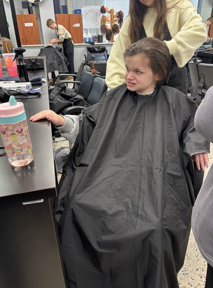 student smiling in mirror while getting a haircut
