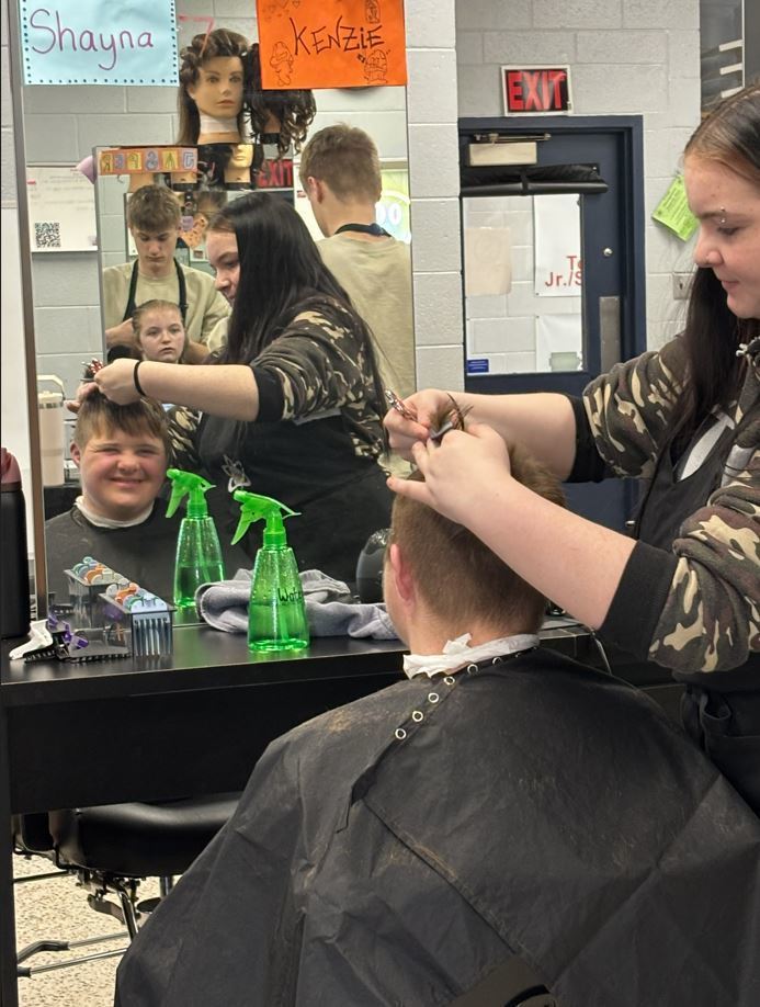student smiling in mirror while getting haircut
