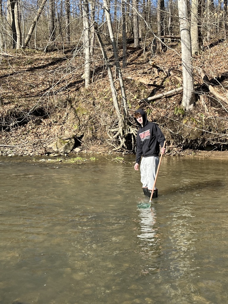 photo a student in the middle of the stream with waders on 