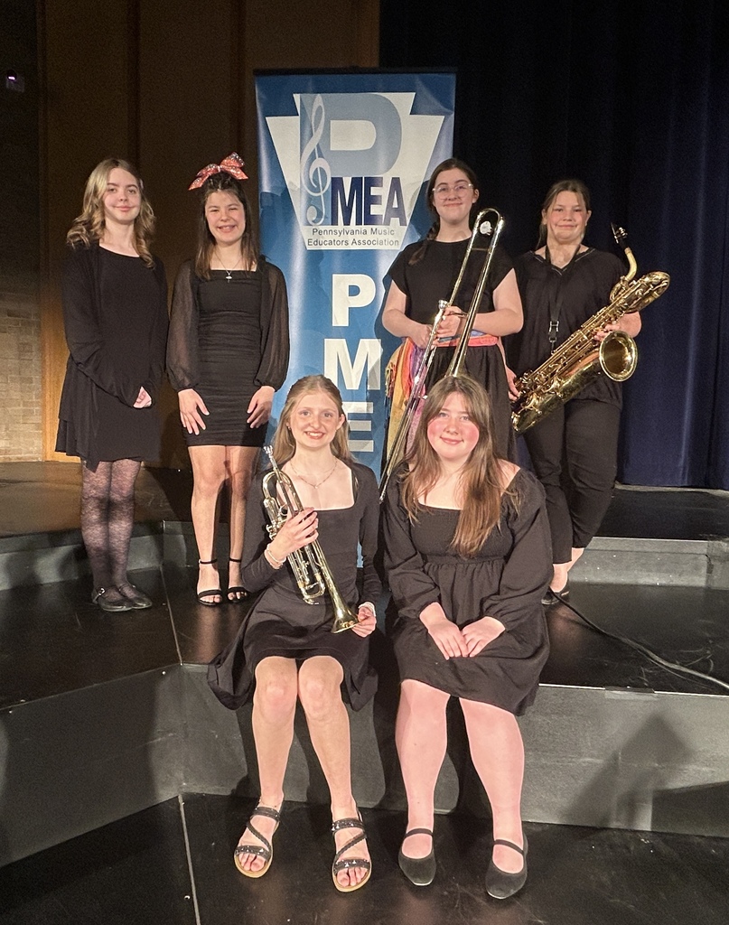 6 students in front of the PMEA Jazz sign with instruments and smiles