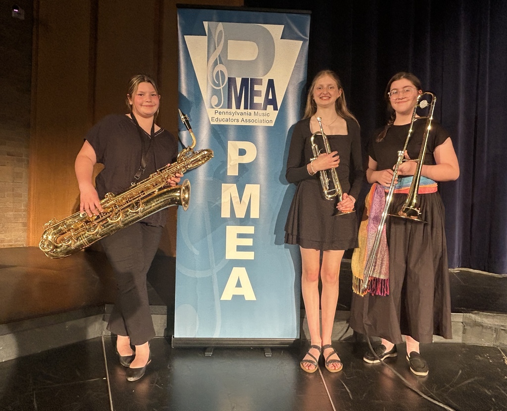 3 students in front of the PMEA Jazz sign with instruments and smiles