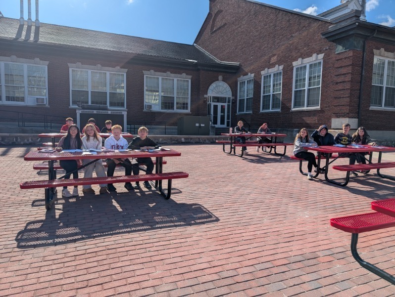 Class of students outside at tables on the terrace
