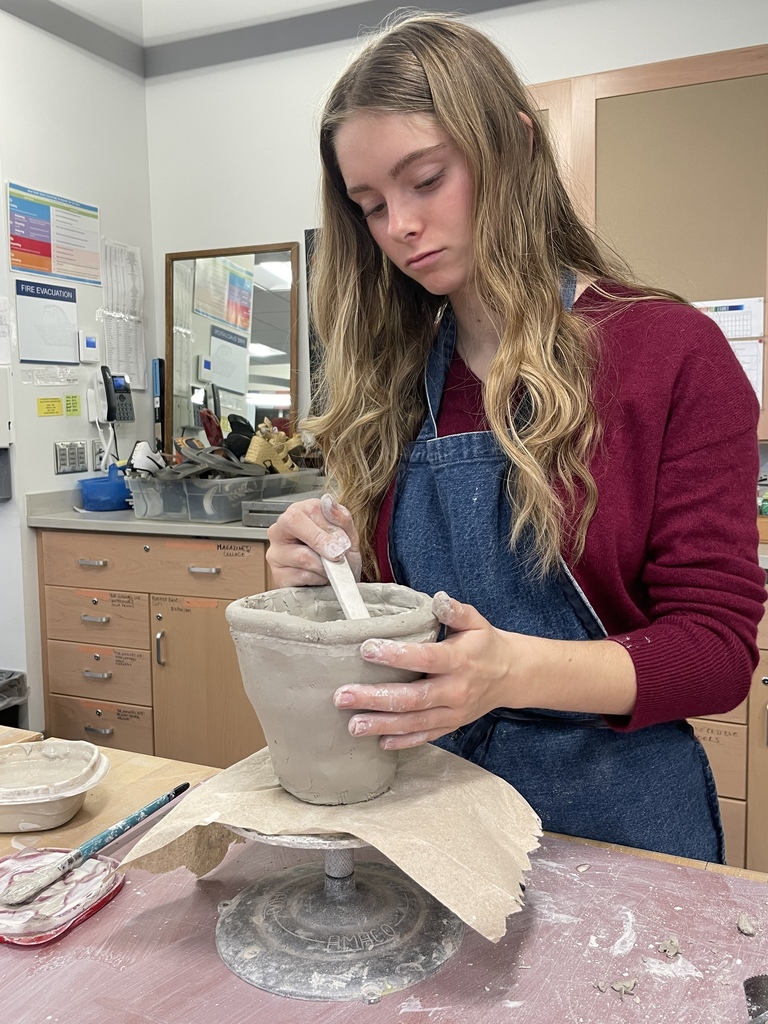 Student joining coils in a clay pot