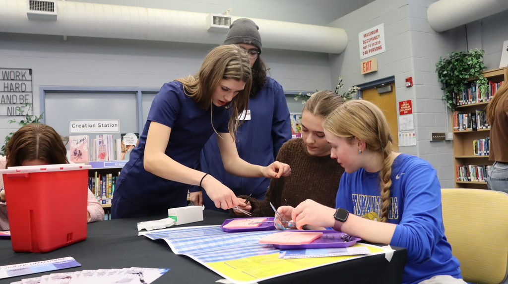 Students sitting at a table demoing how to do medical stitches