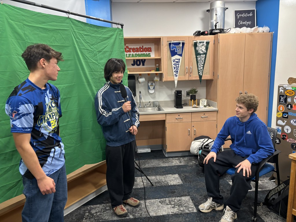 Students in front of a green screen getting ready to record