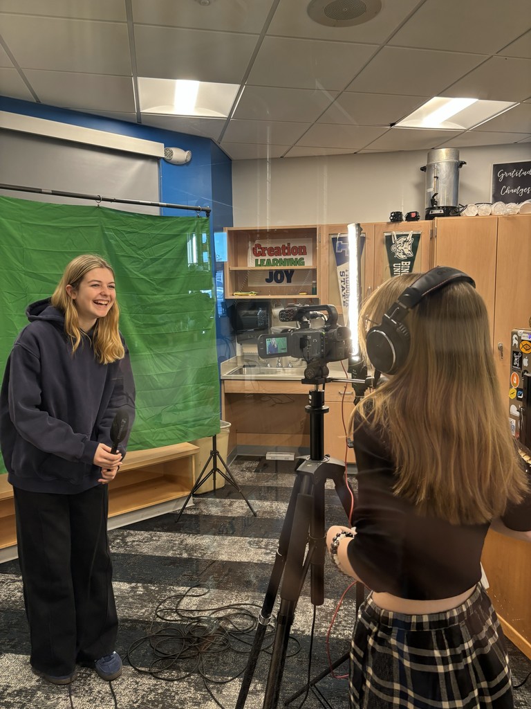 Student filming another student in front of a green screen