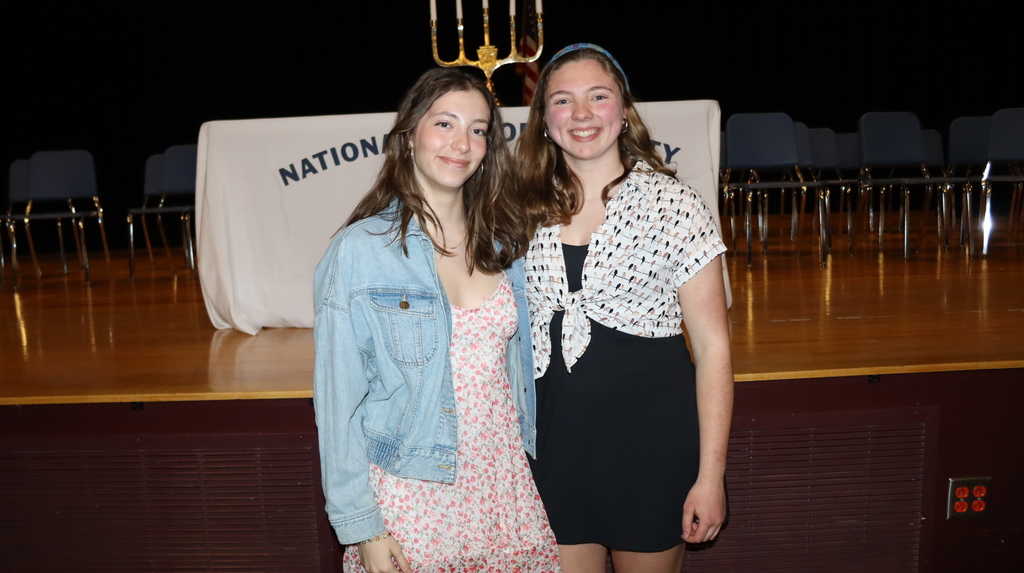 Two students smile in front of the NHS banner