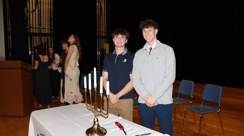 Two students stand behind NHS table and candles