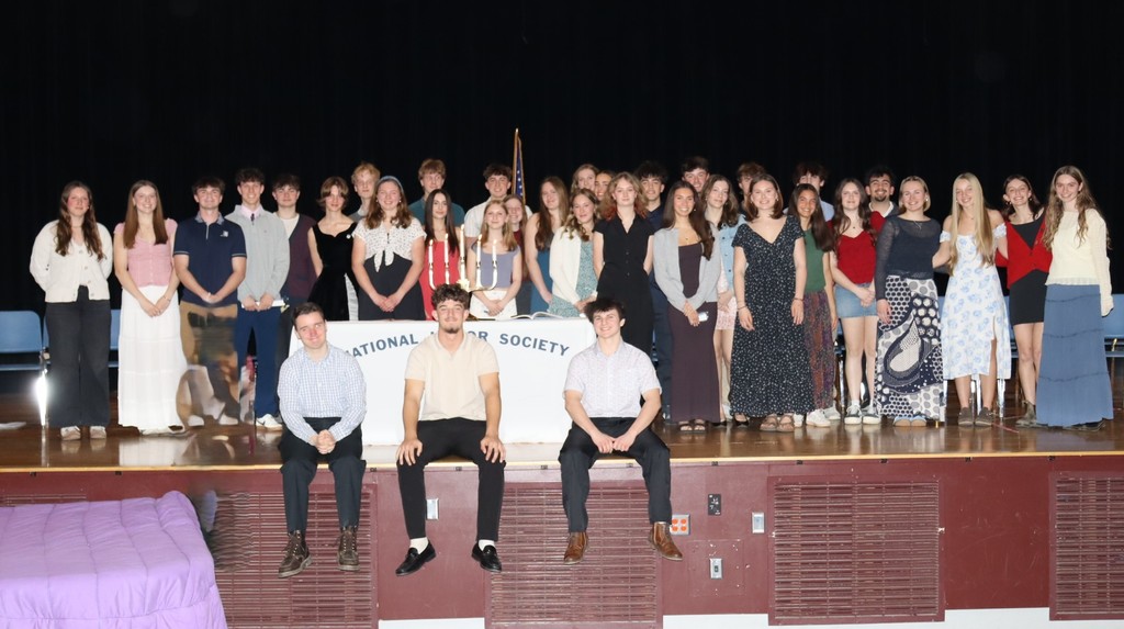 Students sitting and standing on the stage with the NHS banner