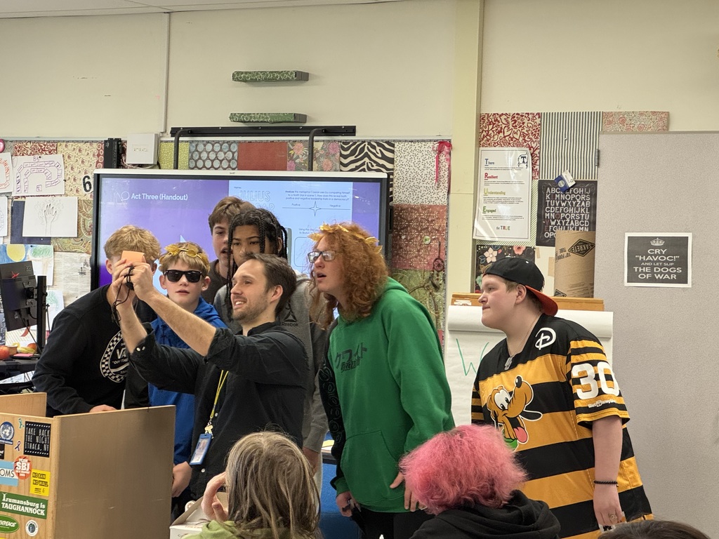 Teacher holding up index card with students crowded around to read it