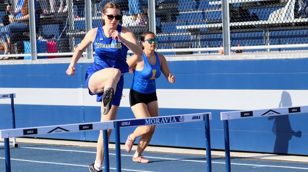 Two students run and do hurdles
