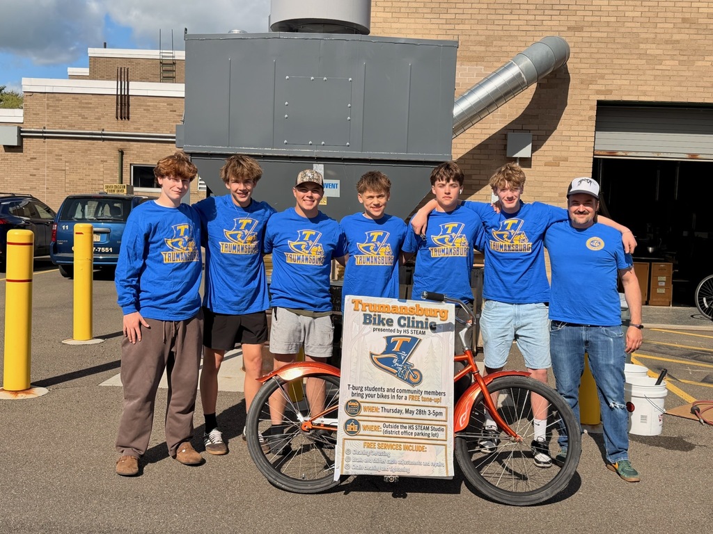 Students and advisor standing in a row behind a bike and large poster