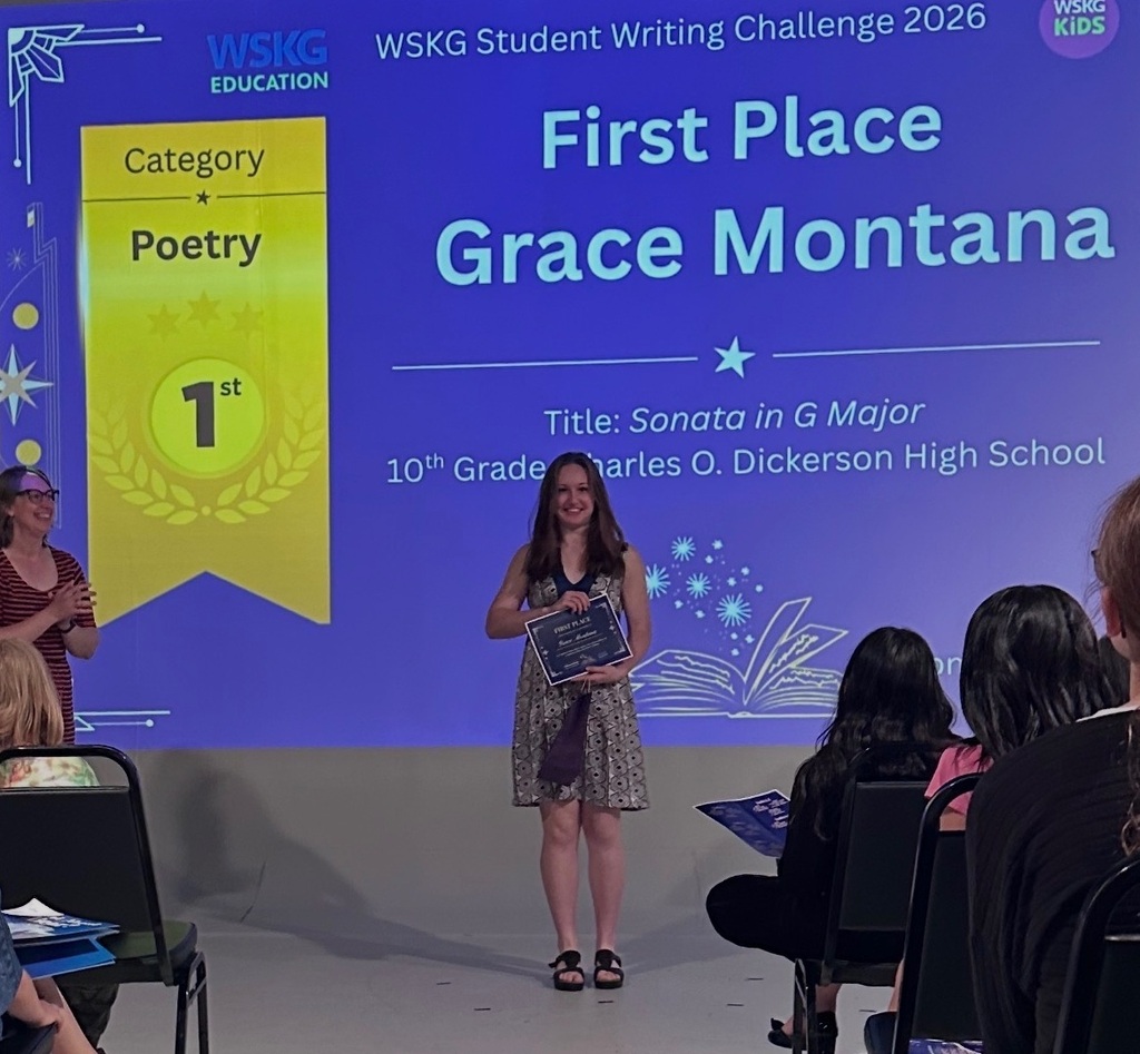 Person holding an award in front of a screen with first place