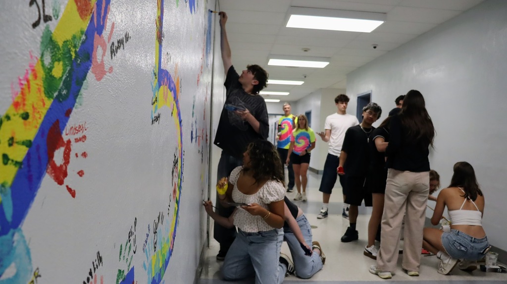 Students paint the wall while others look on