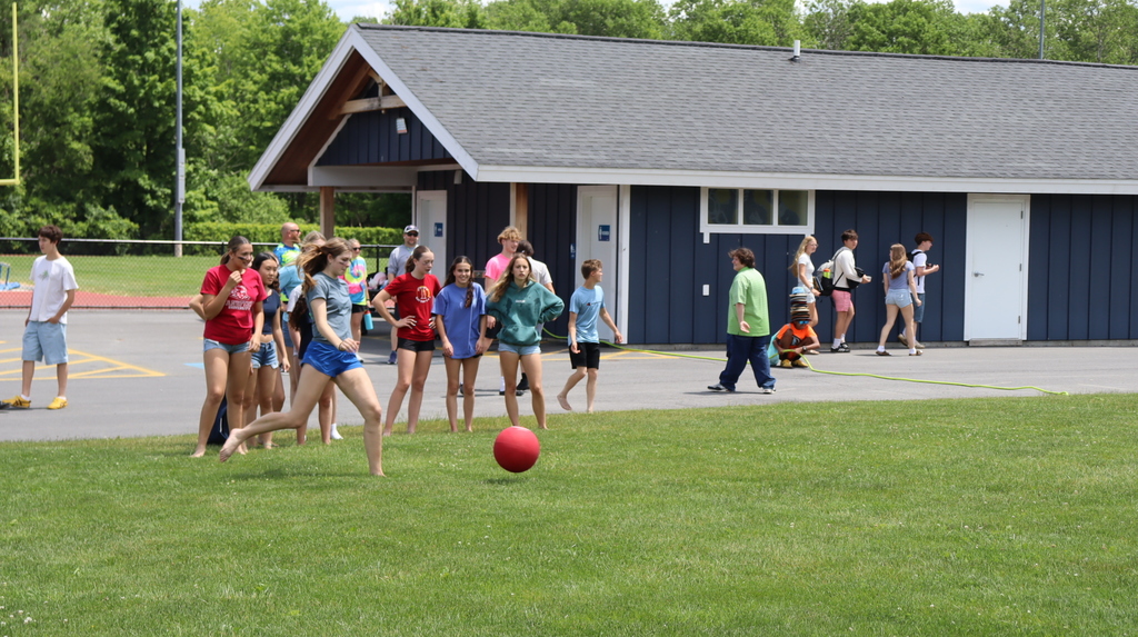 Students kick a ball outside in the grass