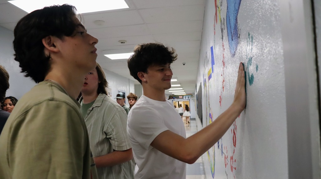Students smile and place handprints on the wall