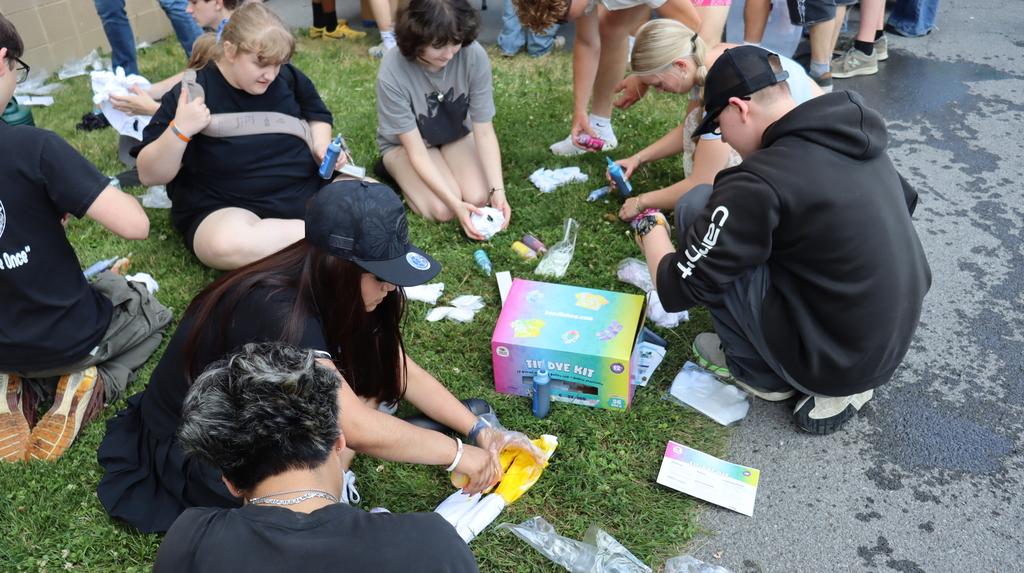 students kneeling in the grass, making tie die