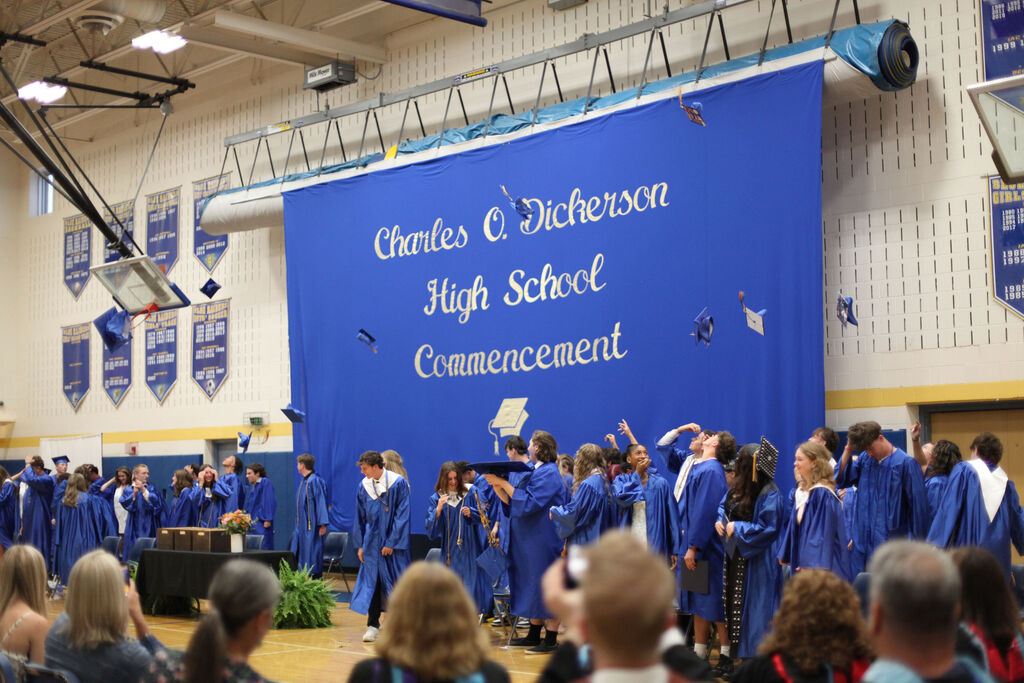 Students tossing caps with commencement banner behind them