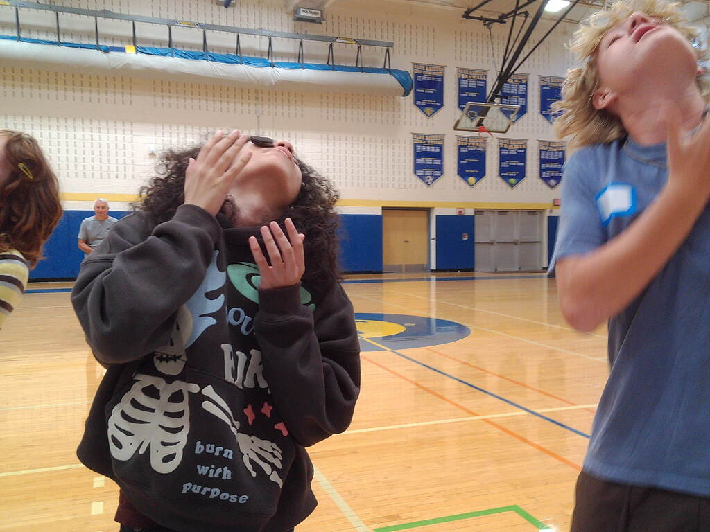 Students looking up while balancing cookies on their faces