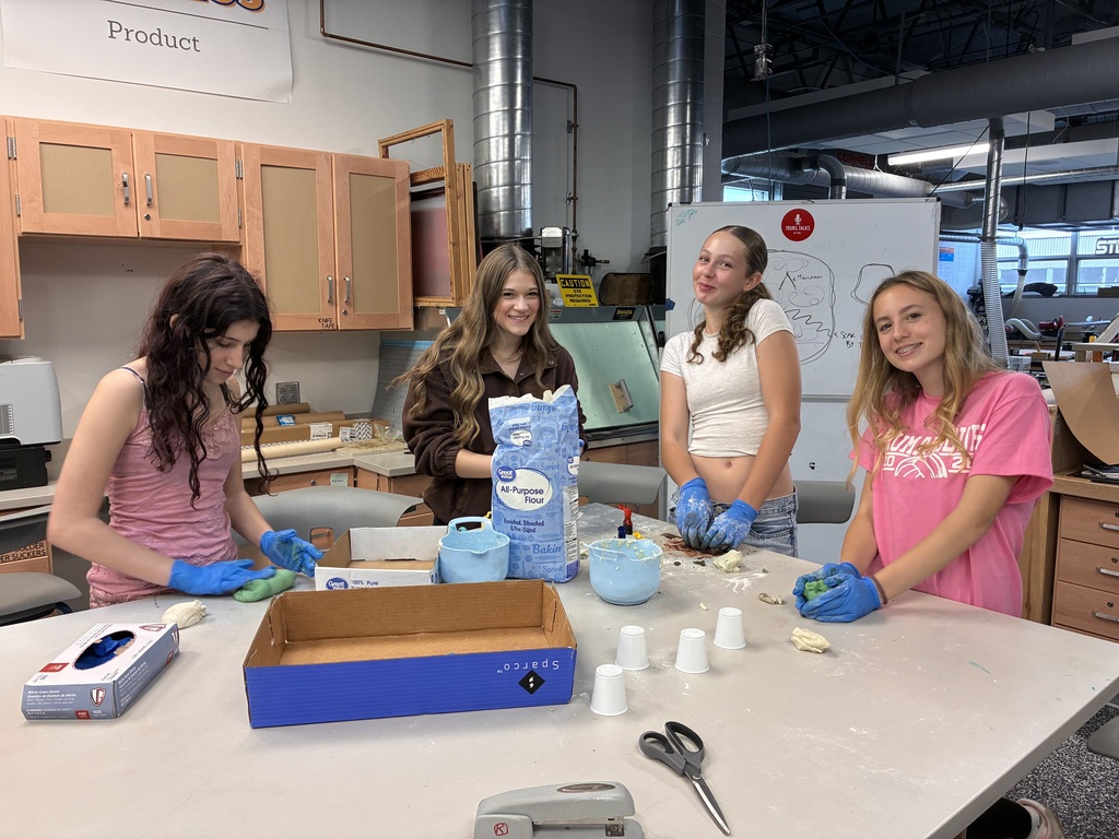 students with gloves smiling at the camera with ingredients out