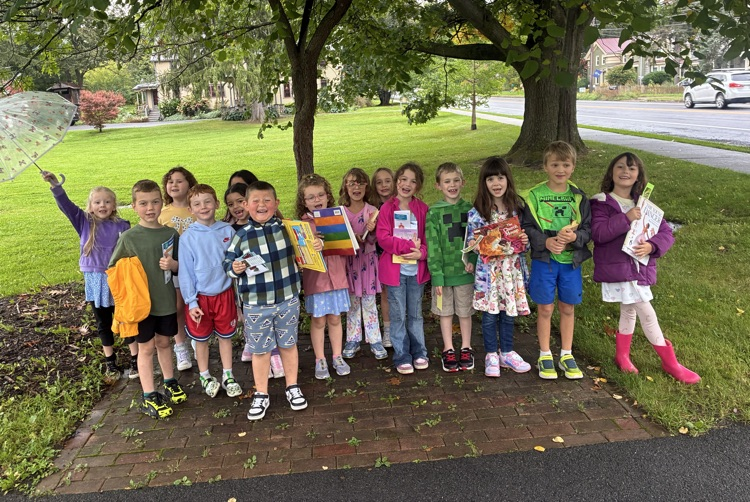 students line up under a tree with their book 