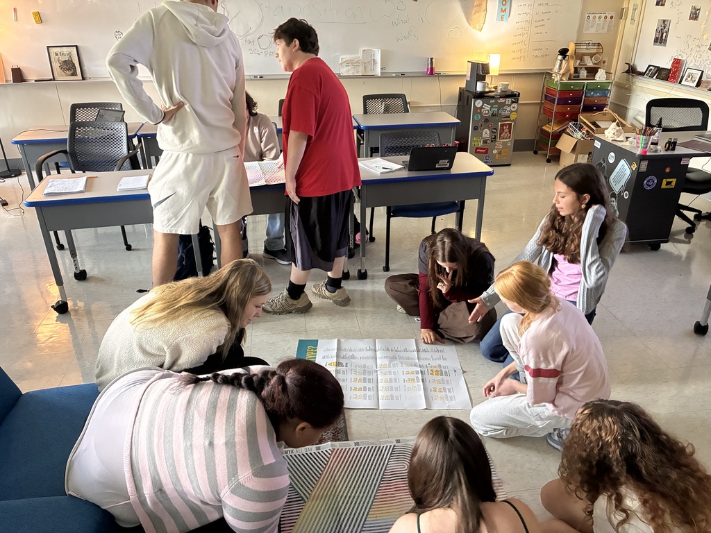 students sitting on floor of classroom over a poster