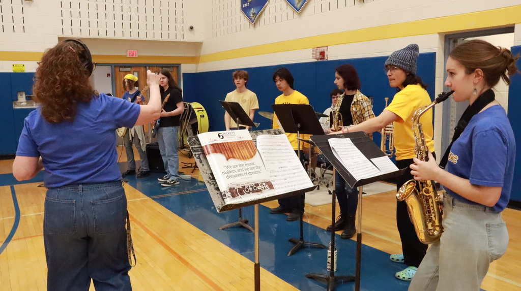 Students in blue and gold playing instruments in a gym