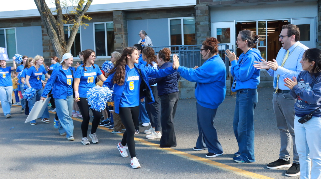 Students in blue high fiving adults in blue