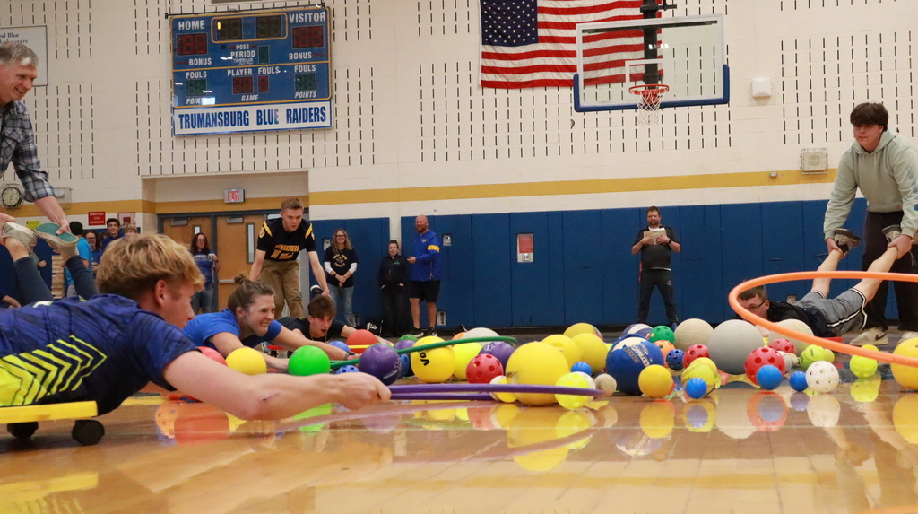 Students reaching forward with hula hoops to capture balls on the ground