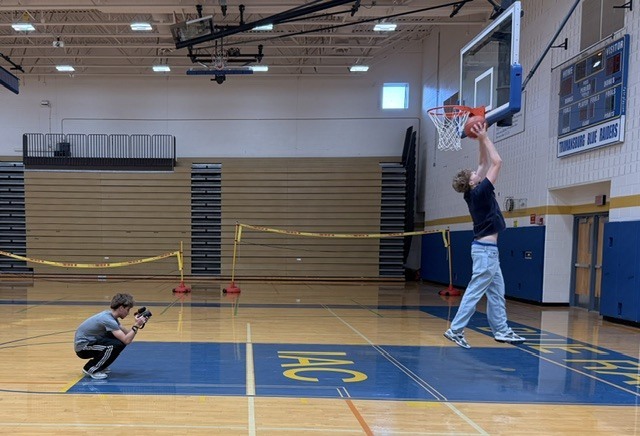 Student making layup while another student takes a picture
