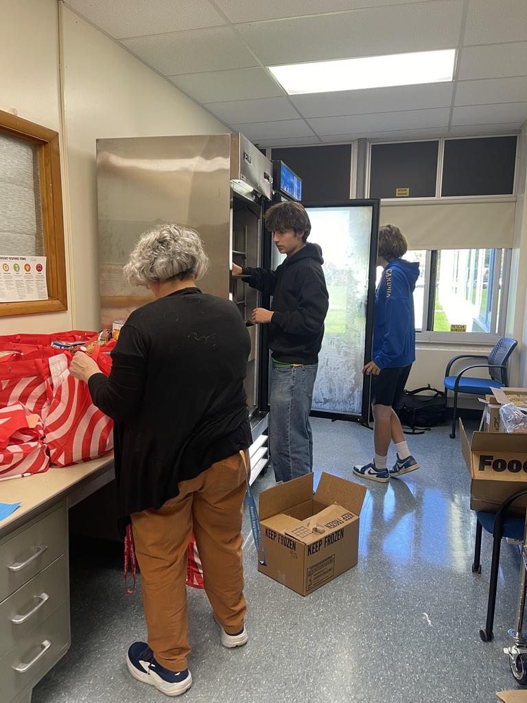 Three people standing in front of bags and refridgerators