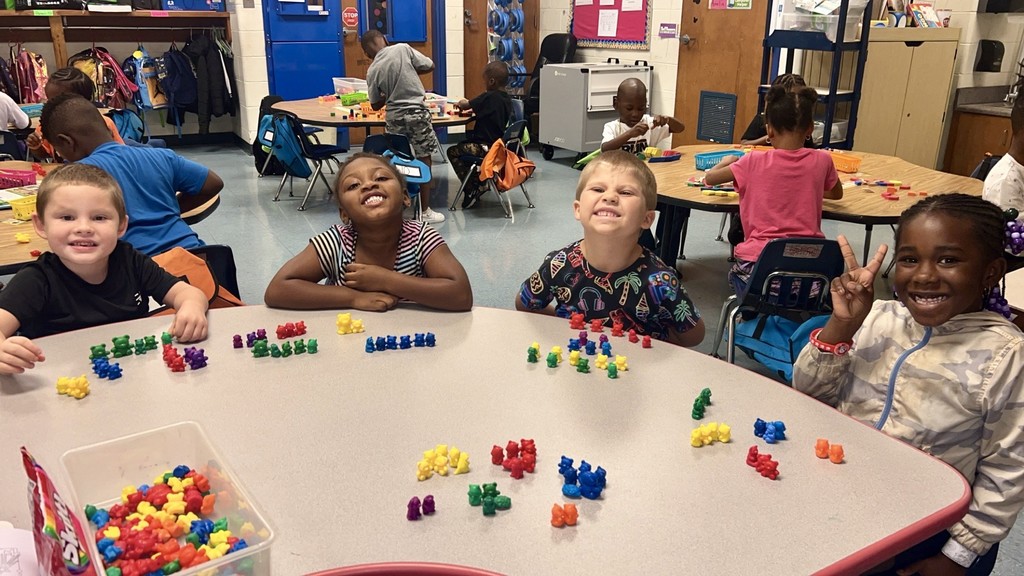 variety of colors and shape of bears, squares, and different objects used for counting, students, desk, classroom