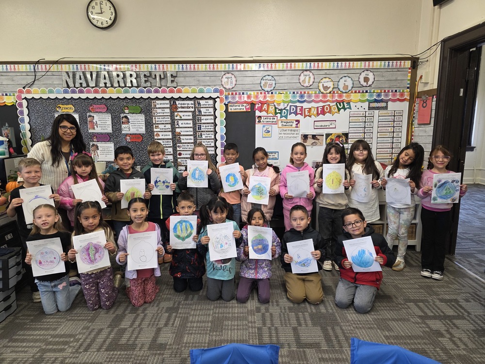 Students hold up their Christmas ornaments and pose for a picture.