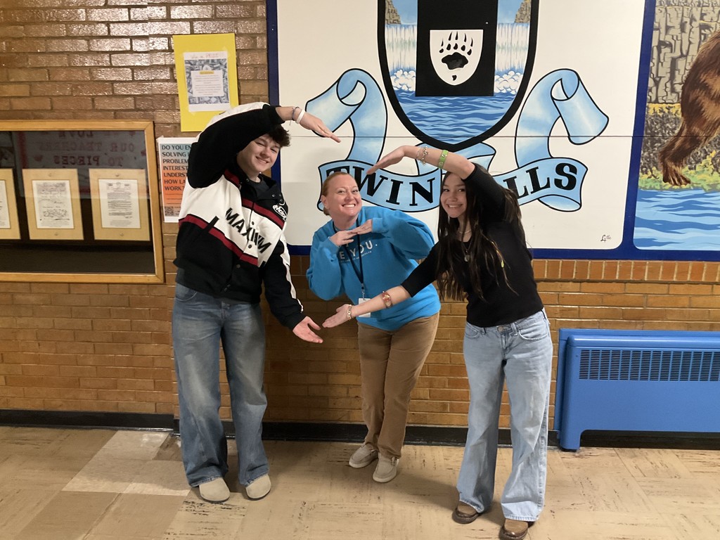 Students make heart shape with arms framing school counselor