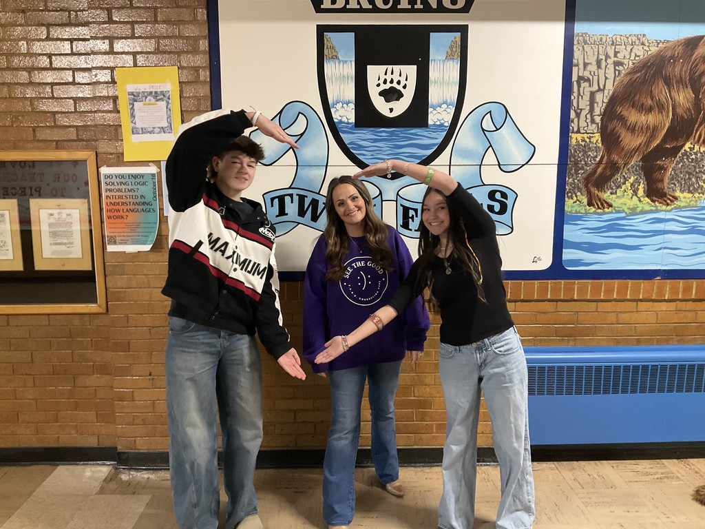 Students make heart shape with arms framing school counselor