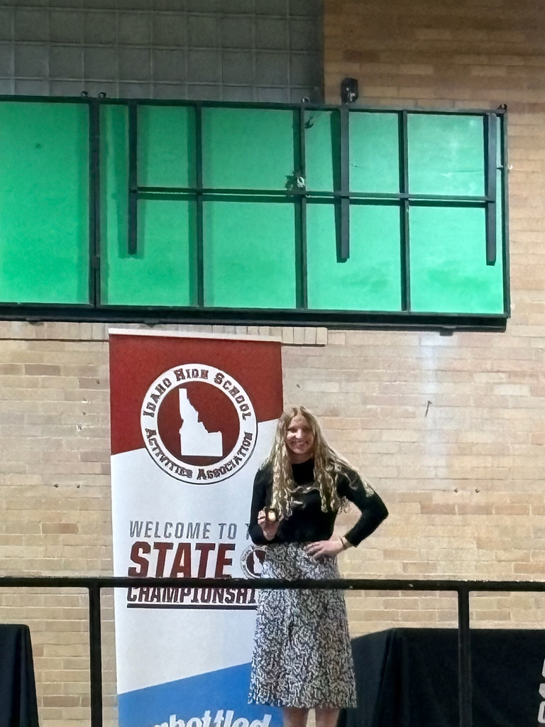Girl standing in front of IHSAA poster with a small medal
